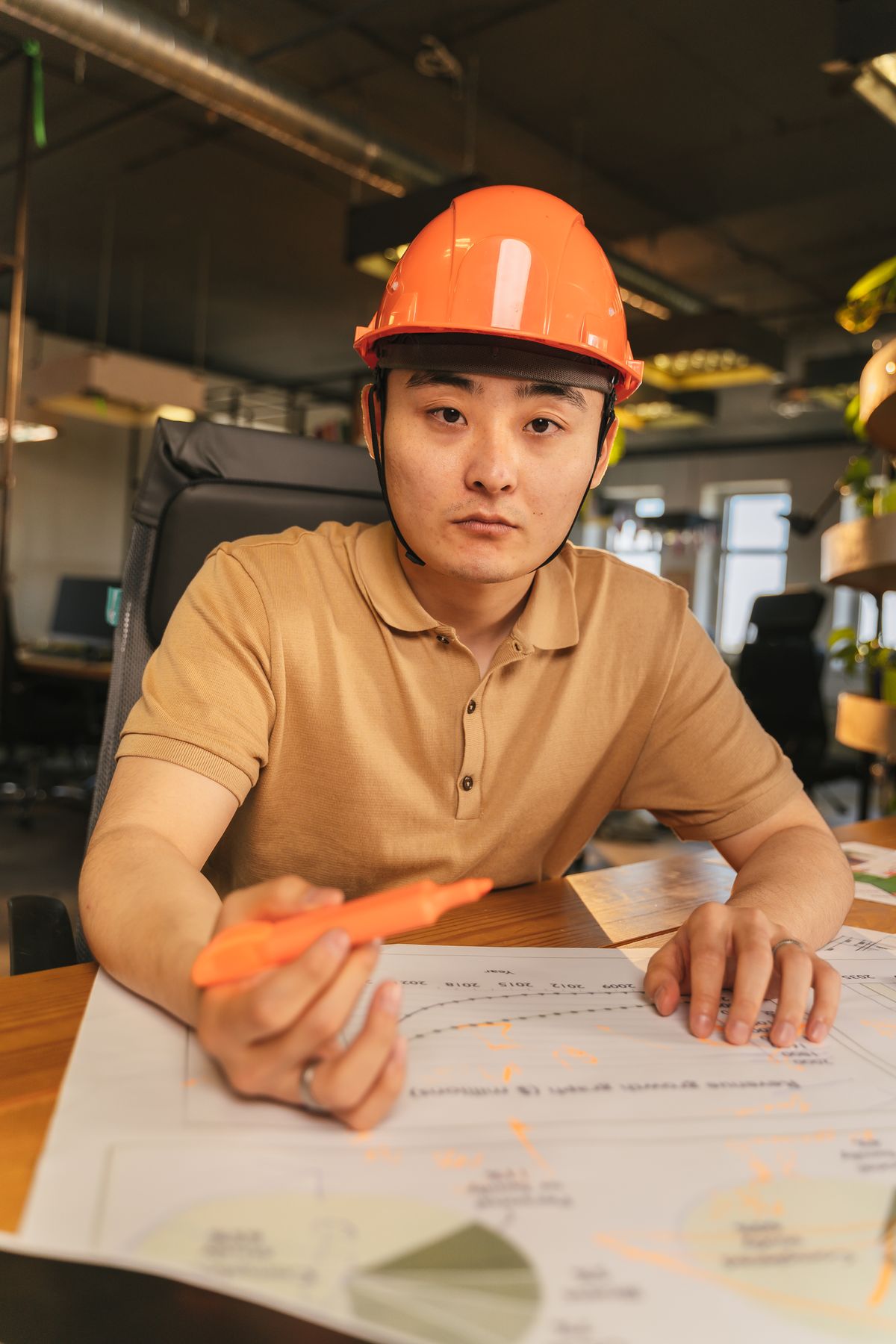 Architect in a safety helmet reviewing a blueprint on site
