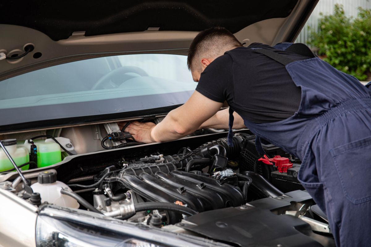 Mechanic in workwear carrying out repair work on a vehicle