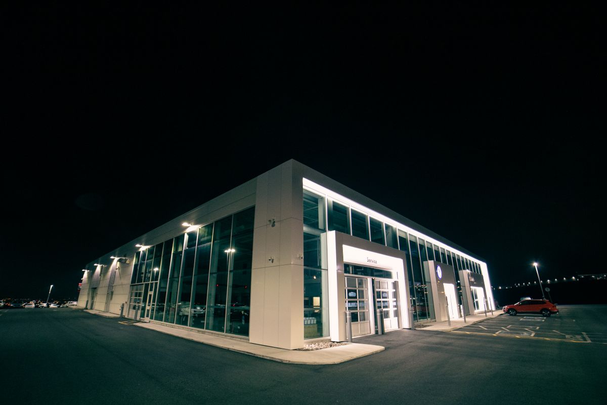 Illuminated dealership building with vehicles on the lot at dusk