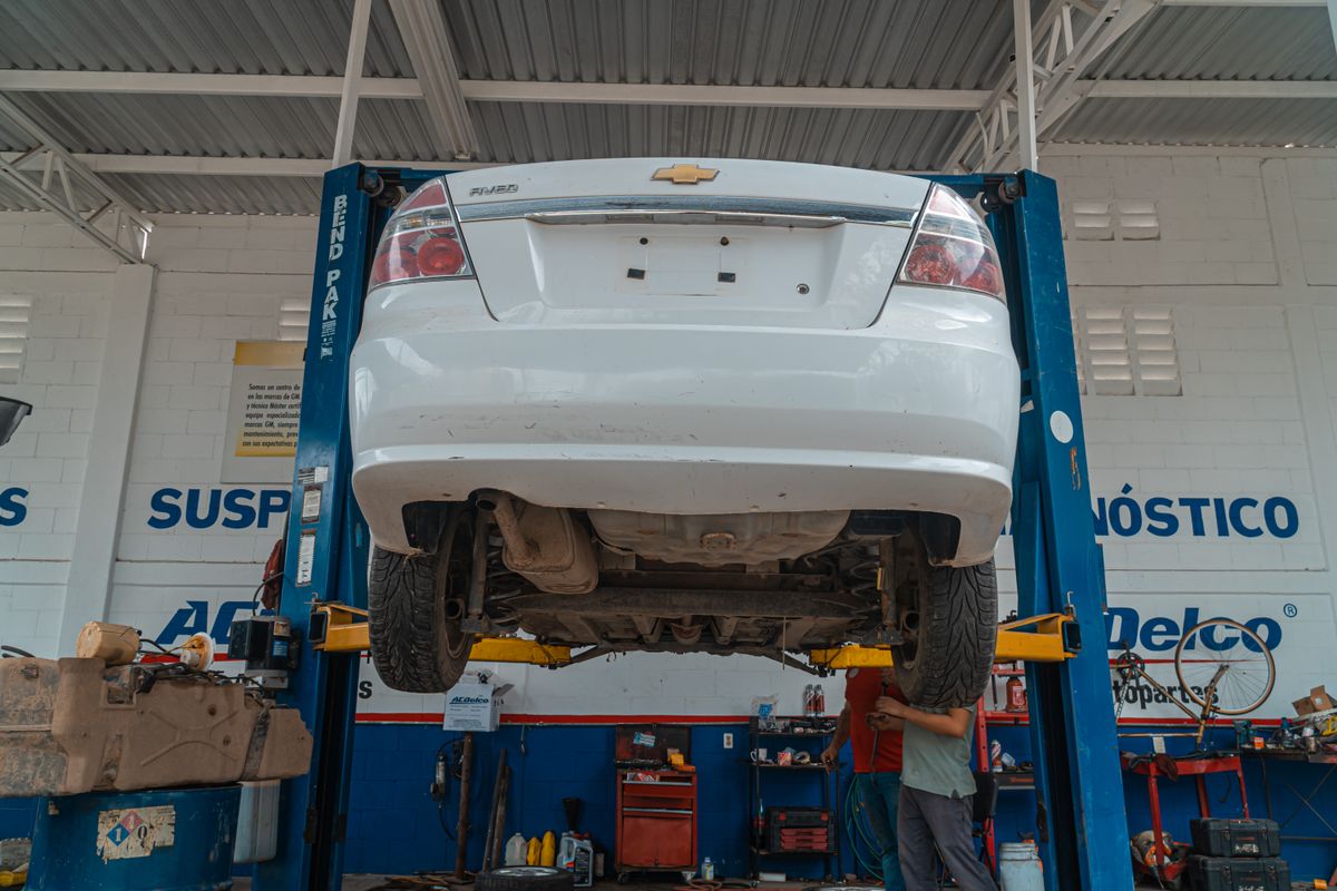 White car raised on a hydraulic lift inside a car repair shop