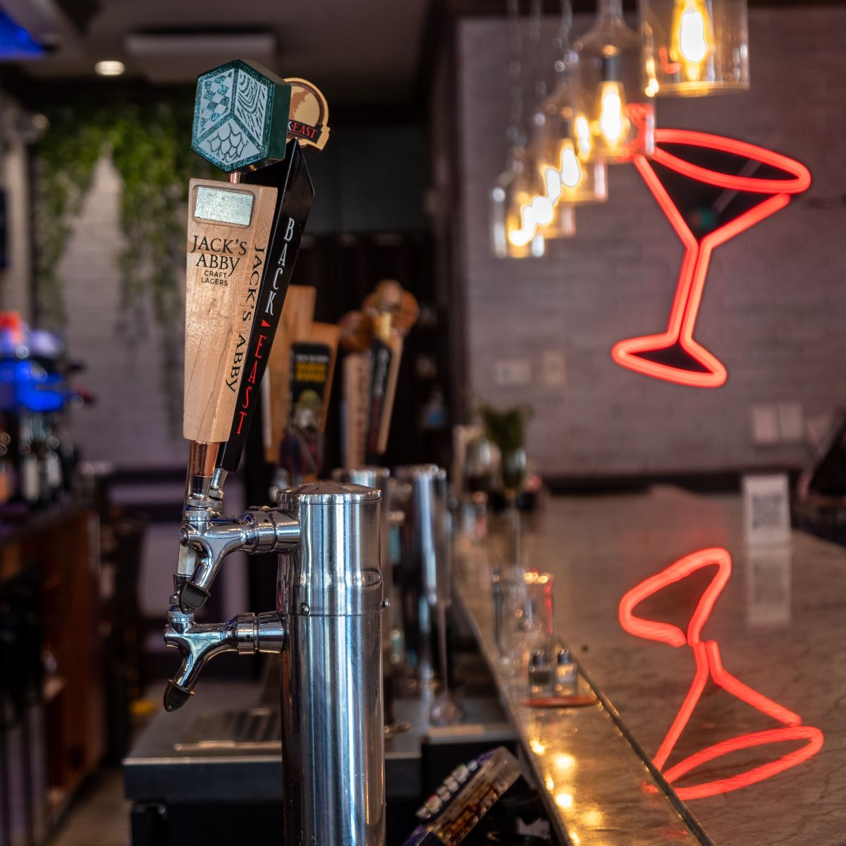 Chic cocktail bar interior with neon sign and back-lit spirits shelf
