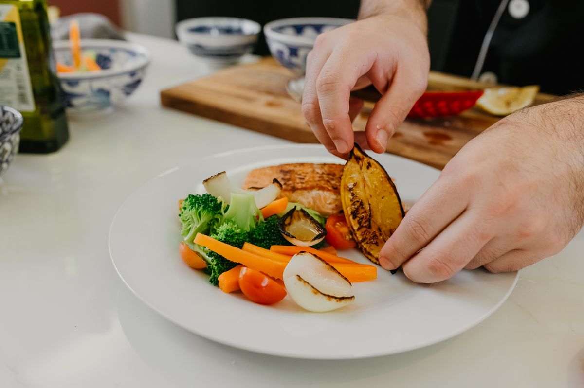 Chef plating grilled salmon with vegetables for a catered function