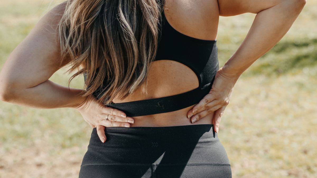 Woman holding her lower back in pain, the kind of symptom that drives chiropractor searches