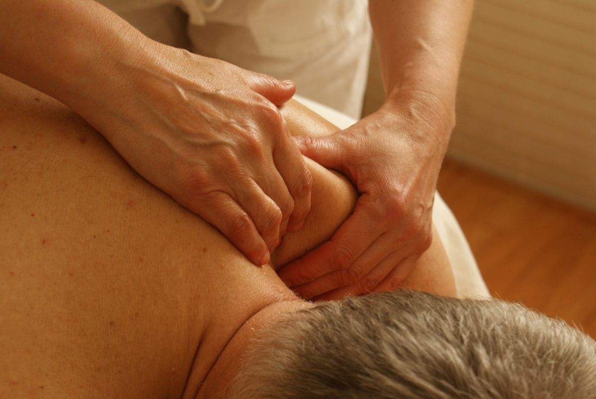Close-up of a practitioner performing hands-on manual therapy on a patient's neck and shoulder
