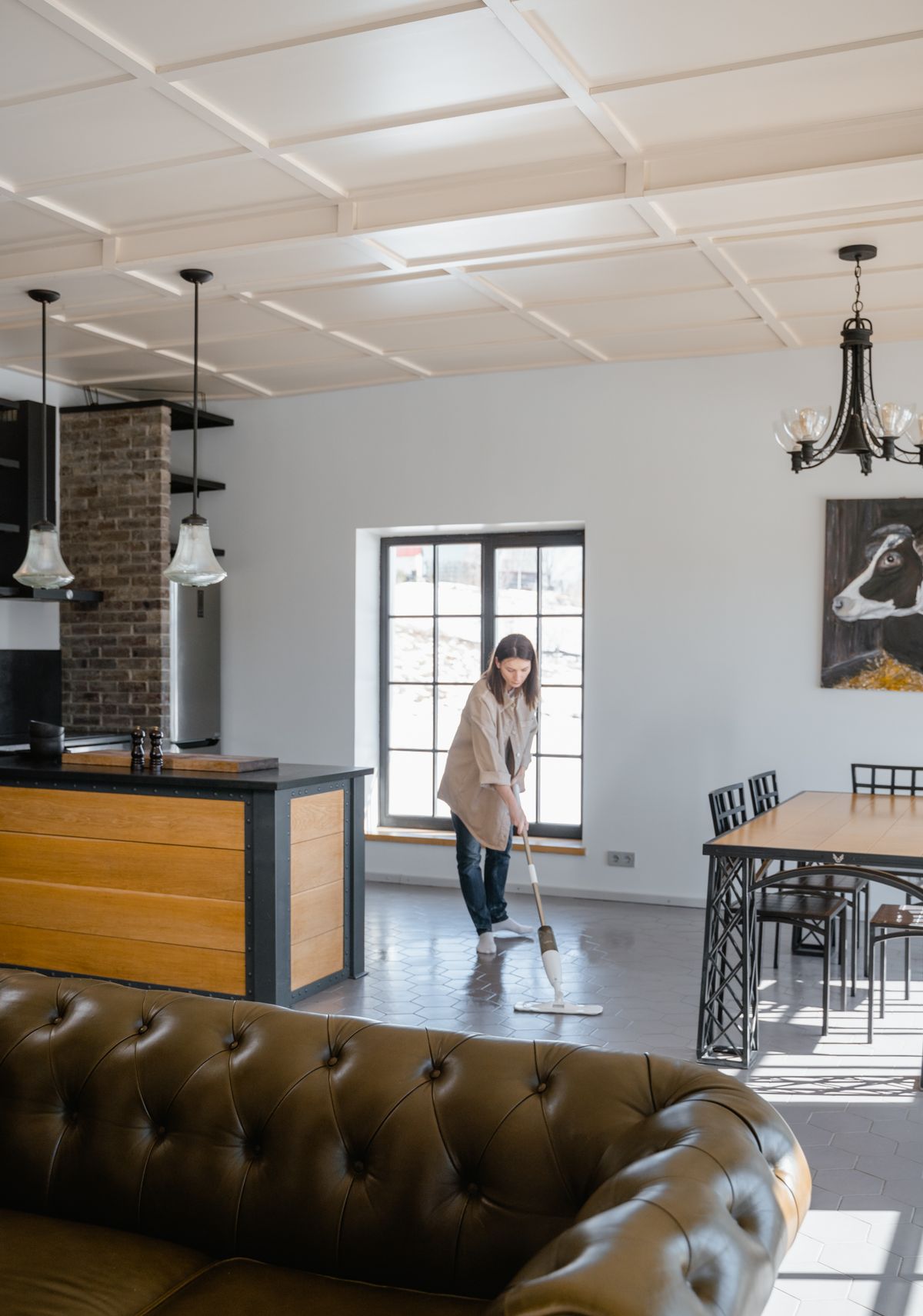 Cleaner mopping the floor of a bright, modern living room