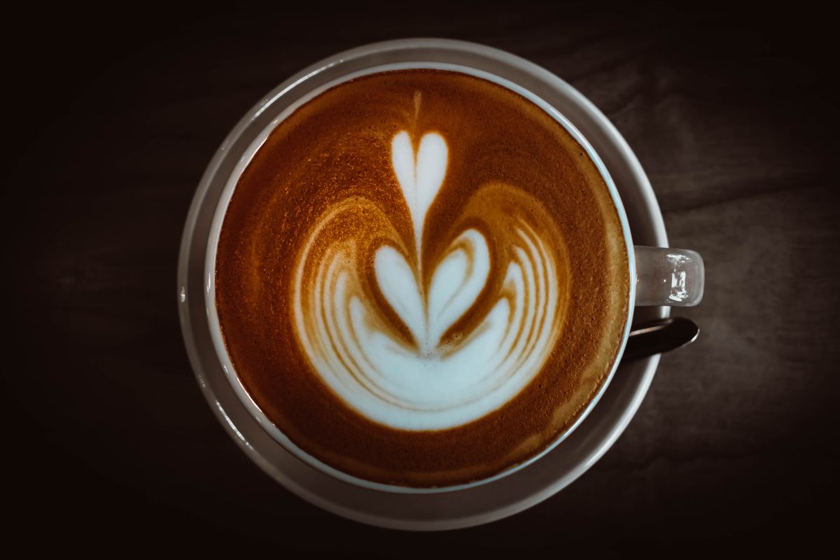 Finished cappuccino with heart-shaped latte art served in a ceramic cup