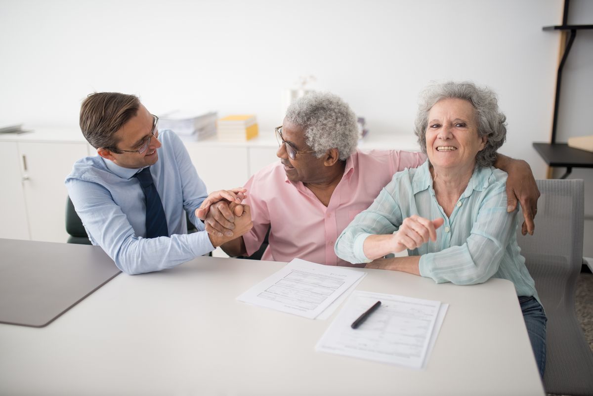 Commercial insurance agent sitting with smiling business clients reviewing a policy in an Edinburgh office