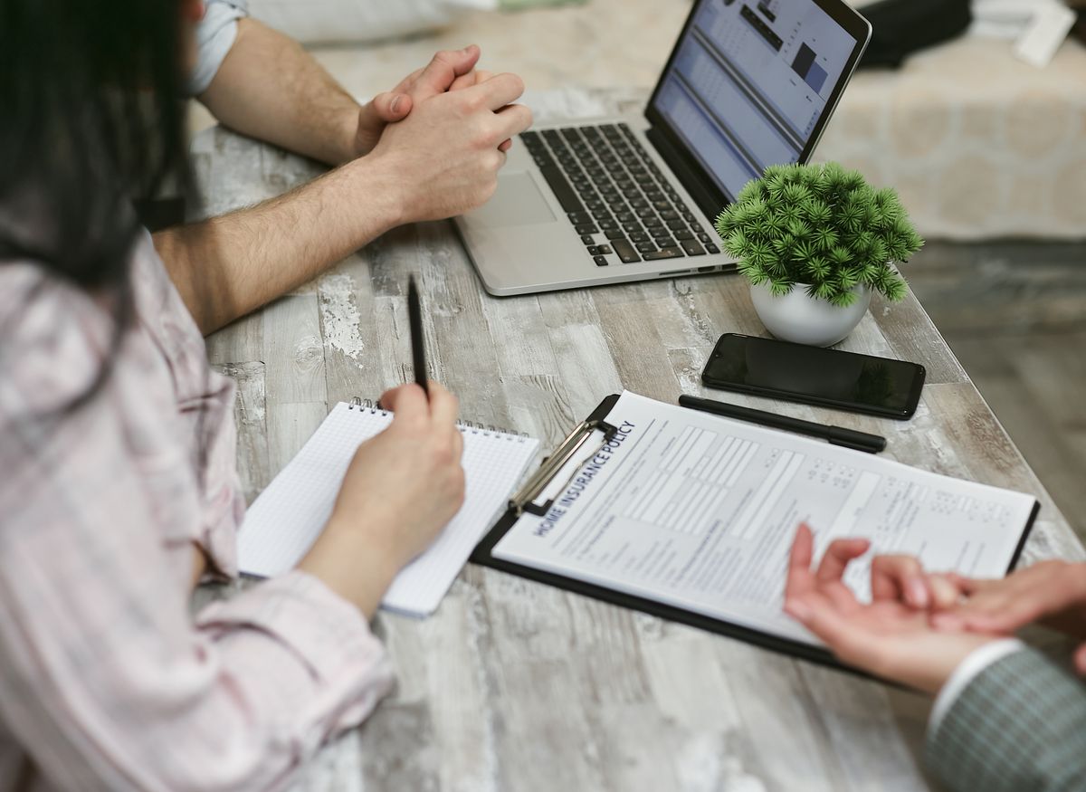 Insurance broker discussing a business insurance policy with clients over a laptop
