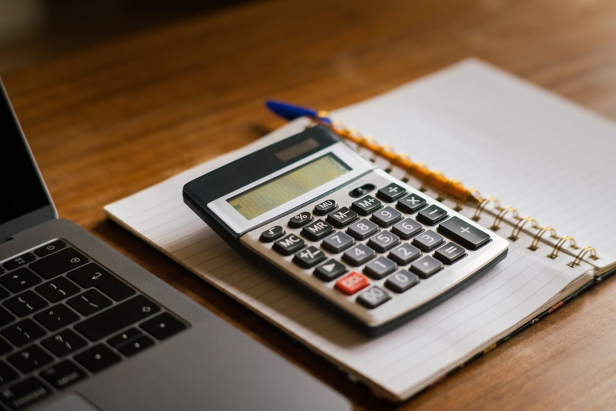Accountant working at a desk calculator, reviewing client financial statements in an Edinburgh CPA office