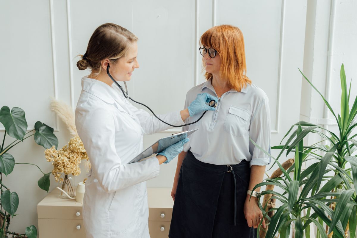 Doctor using a stethoscope to examine a patient in a consultation room