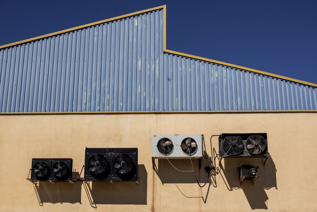 Row of industrial air conditioning and ventilation units mounted on a commercial building wall