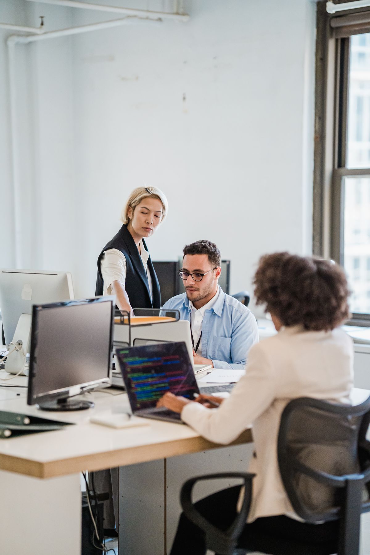 IT consultants collaborating on laptops in an open-plan office