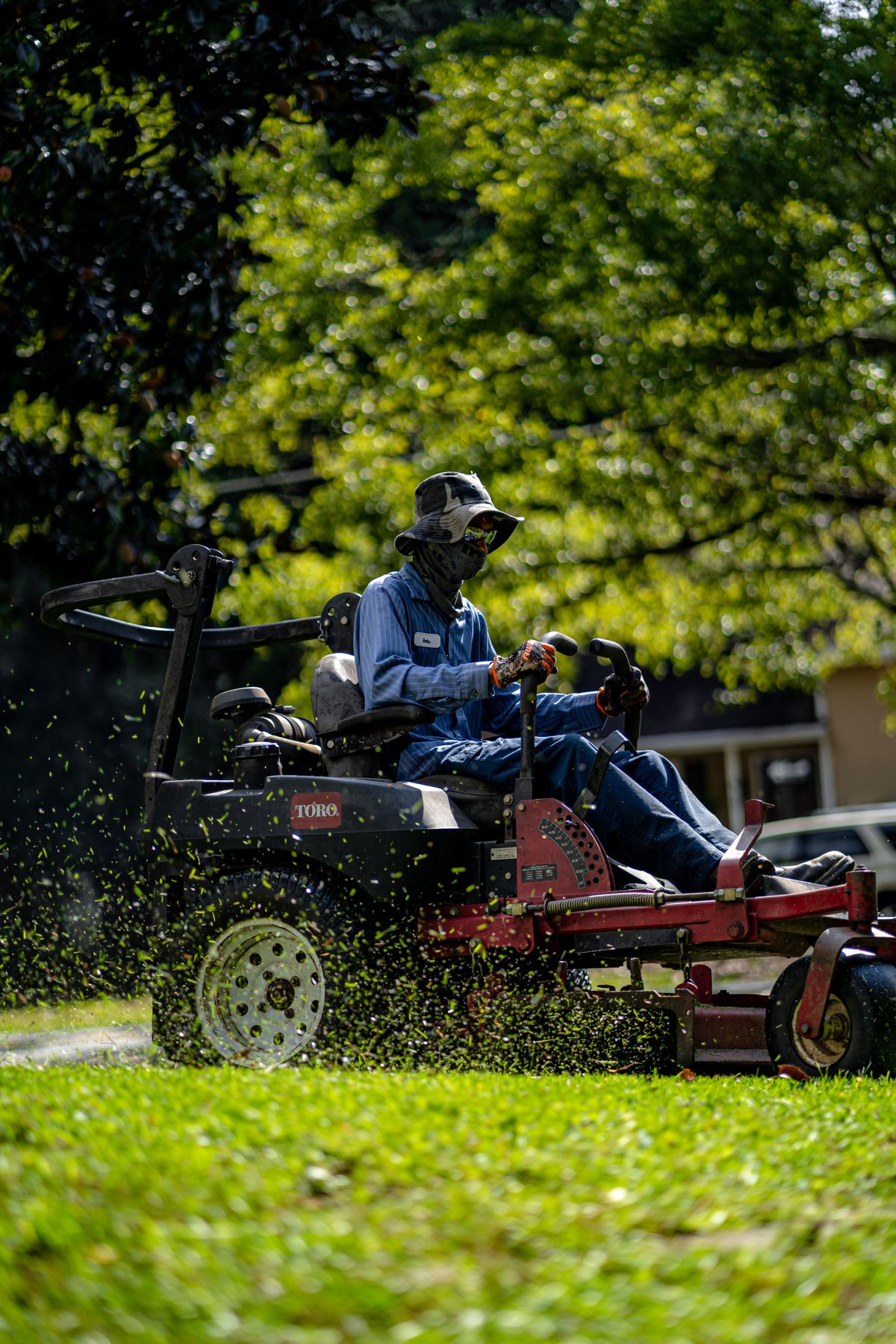 Landscaper mowing a neatly maintained lawn in a residential garden
