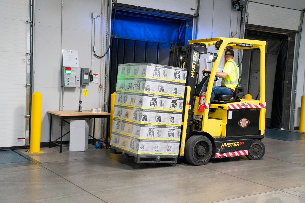 Warehouse operative riding a forklift between racking aisles