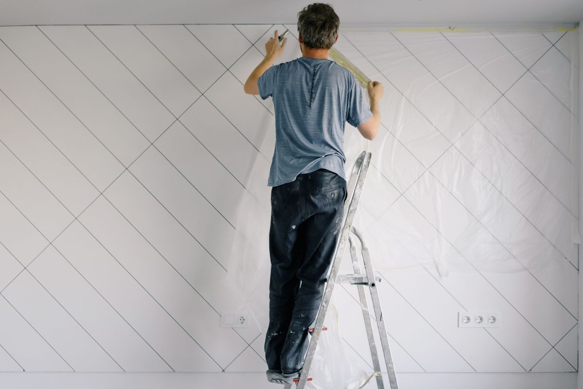 Professional painter applying undercoat to an interior wall in a bright Edinburgh home