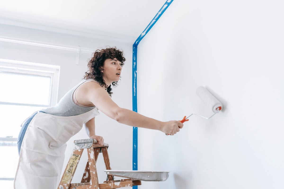 Decorator using a roller brush to apply paint to a wall during a home renovation