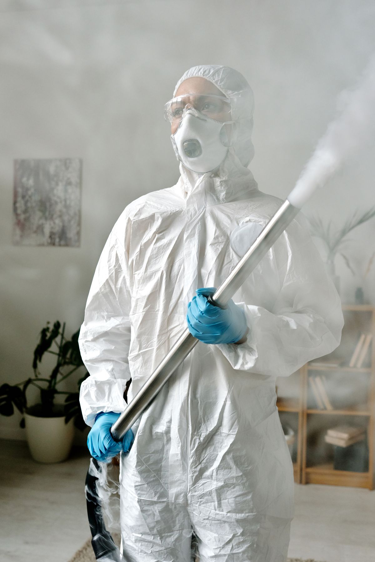 Pest control operative in a protective suit carrying out a fumigation treatment