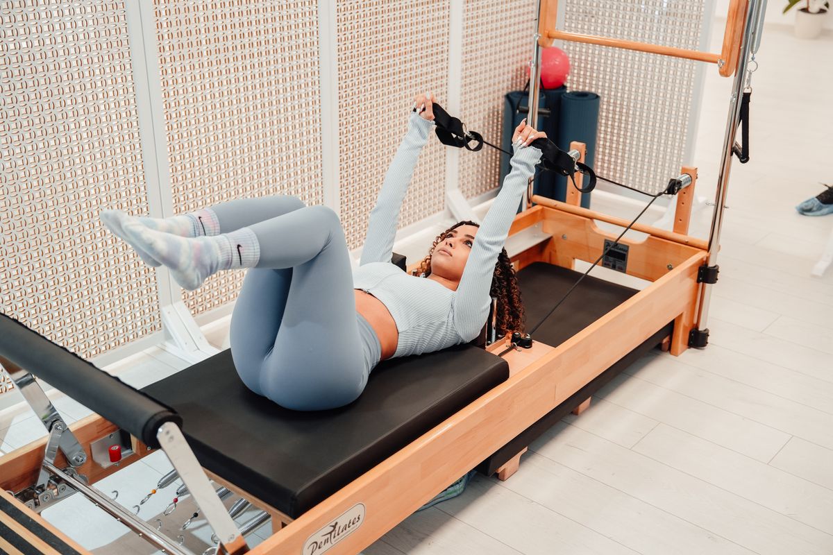 Woman lying on a Pilates reformer machine during a studio session