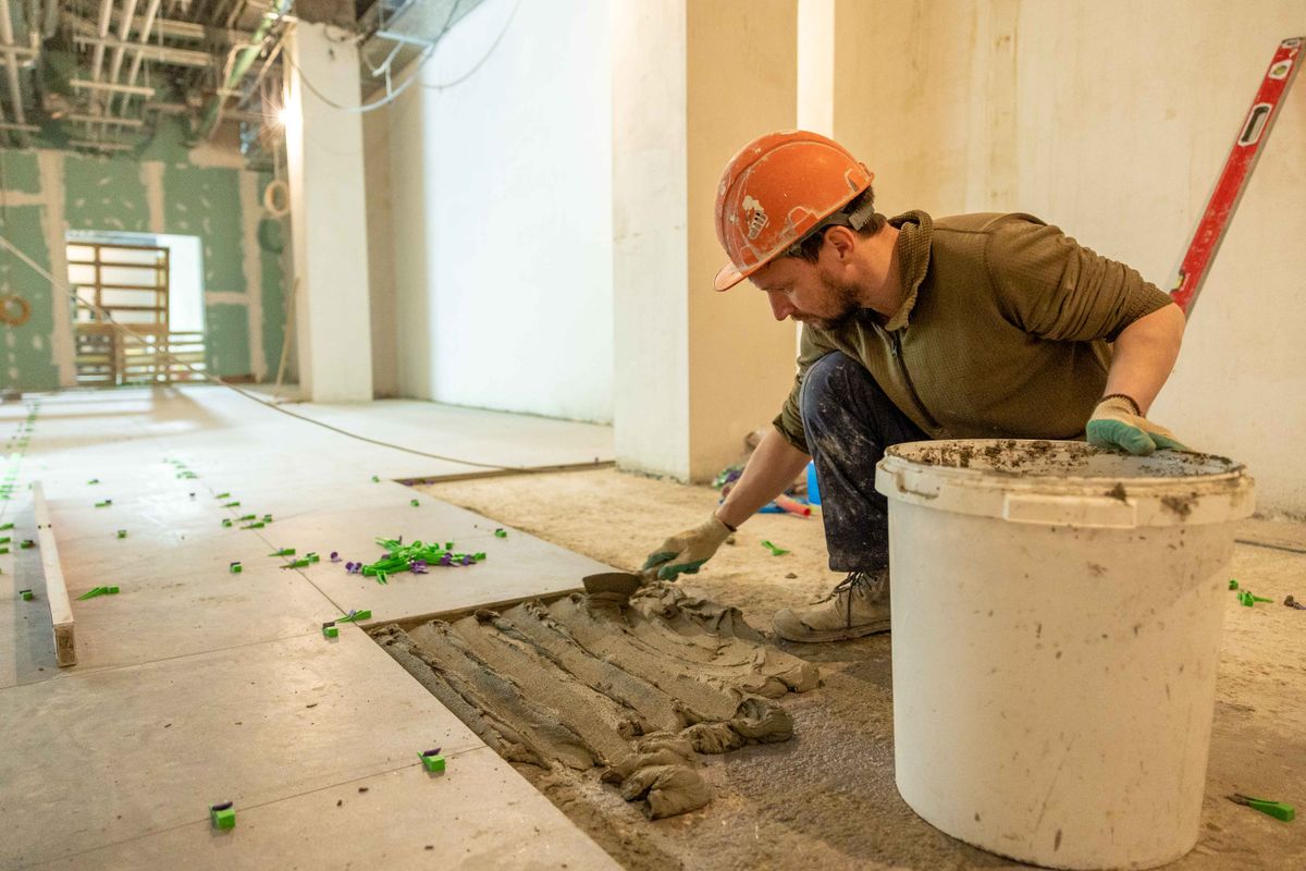 Tradesperson laying floor tile during a bathroom renovation project