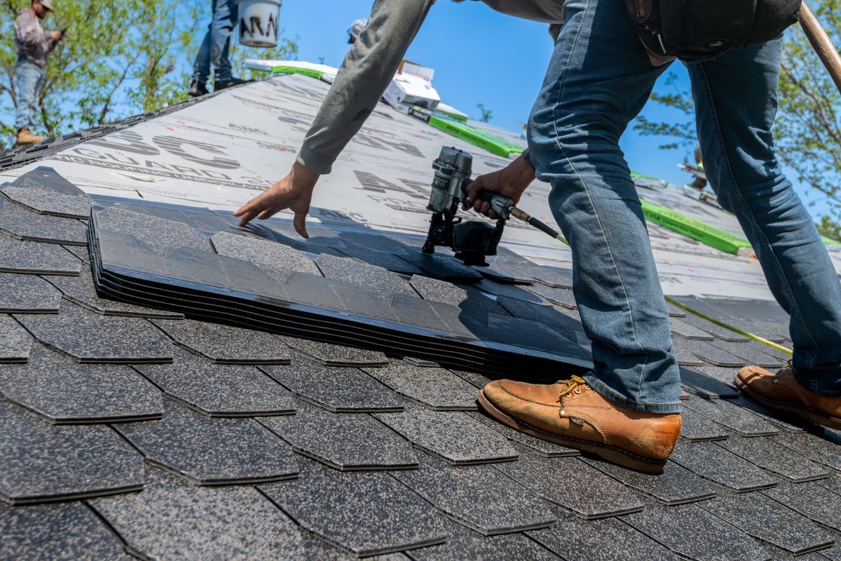 Professional roofer installing new shingles on a residential roof