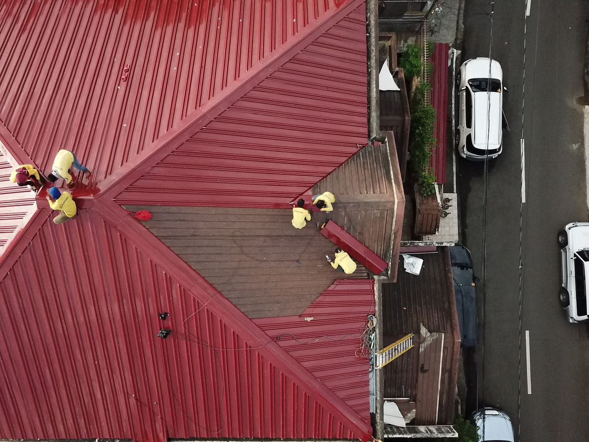 Roofing crew repairing a pitched roof from an aerial viewpoint