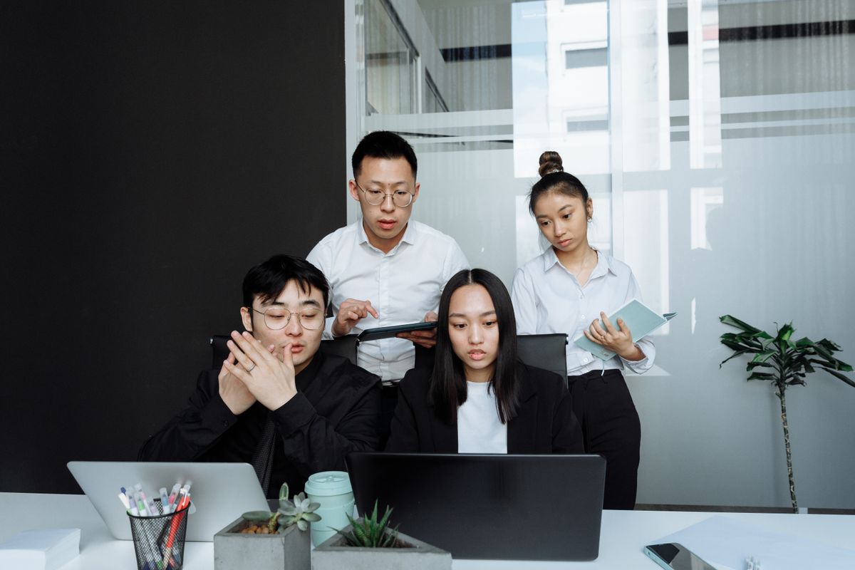 A SaaS company team having a stand-up meeting around a laptop in a modern office