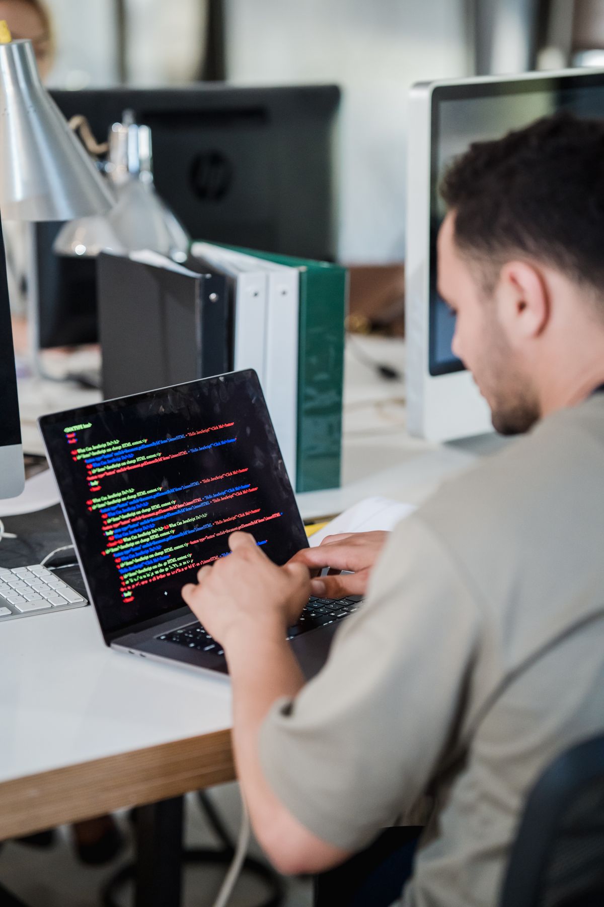 A software developer at a SaaS company focused on coding at a laptop in an open-plan office
