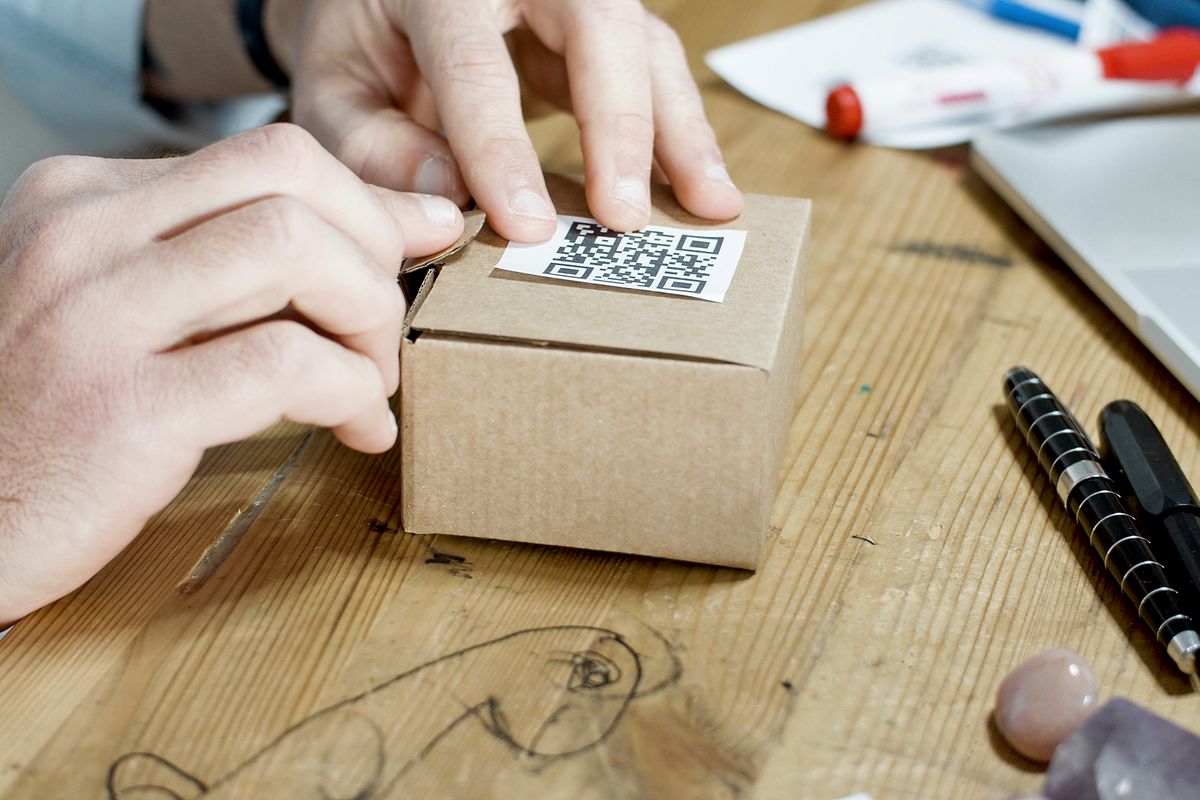 Warehouse worker taping up a branded cardboard box for a Shopify order