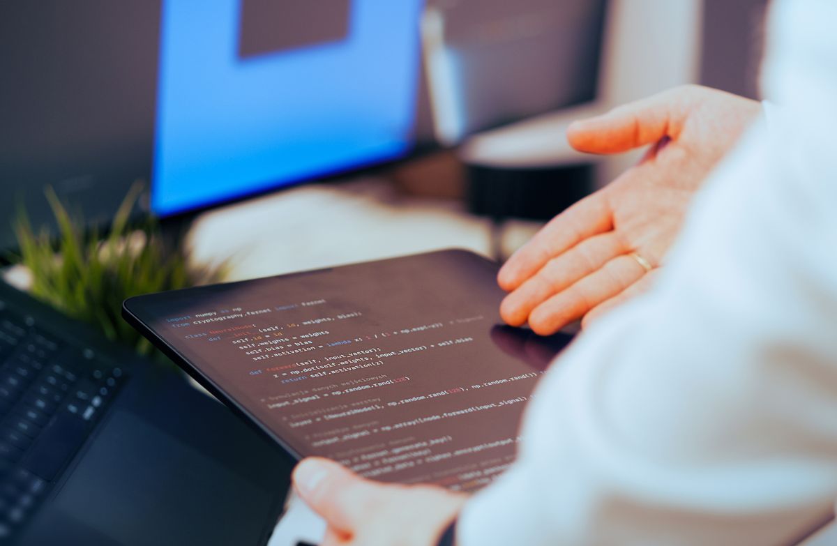 Developer reviewing code on a tablet during a project handover meeting