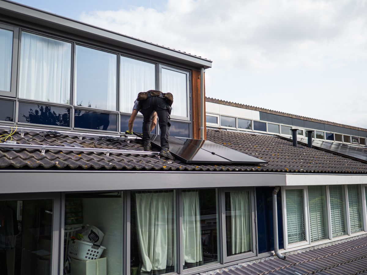 Technician installing solar panels on a residential rooftop in daylight