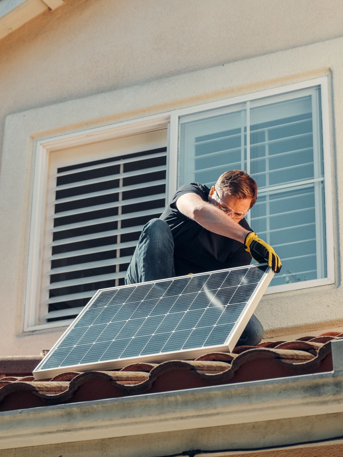 Installer fitting a solar panel to a roof frame during a sunny afternoon