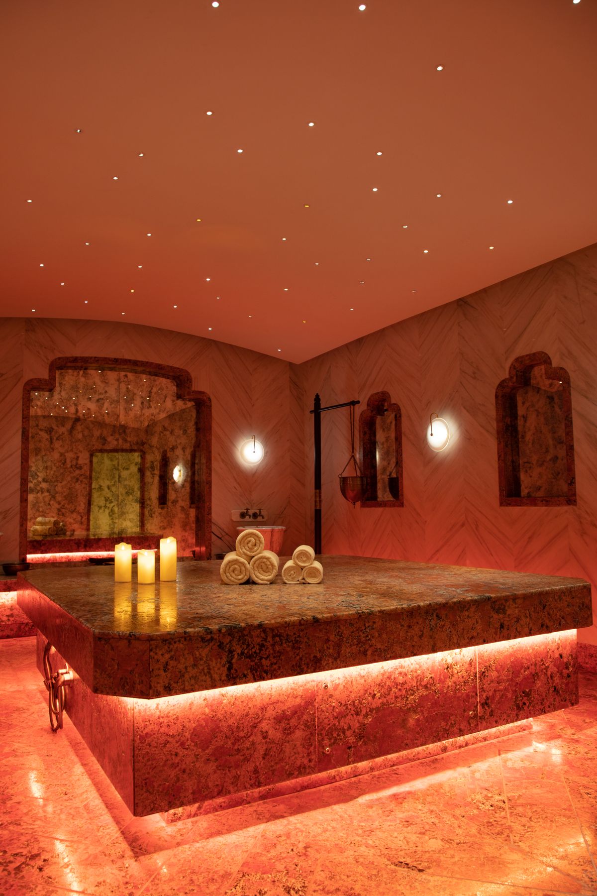 Warm, softly lit hammam-style steam room with towels arranged for guests