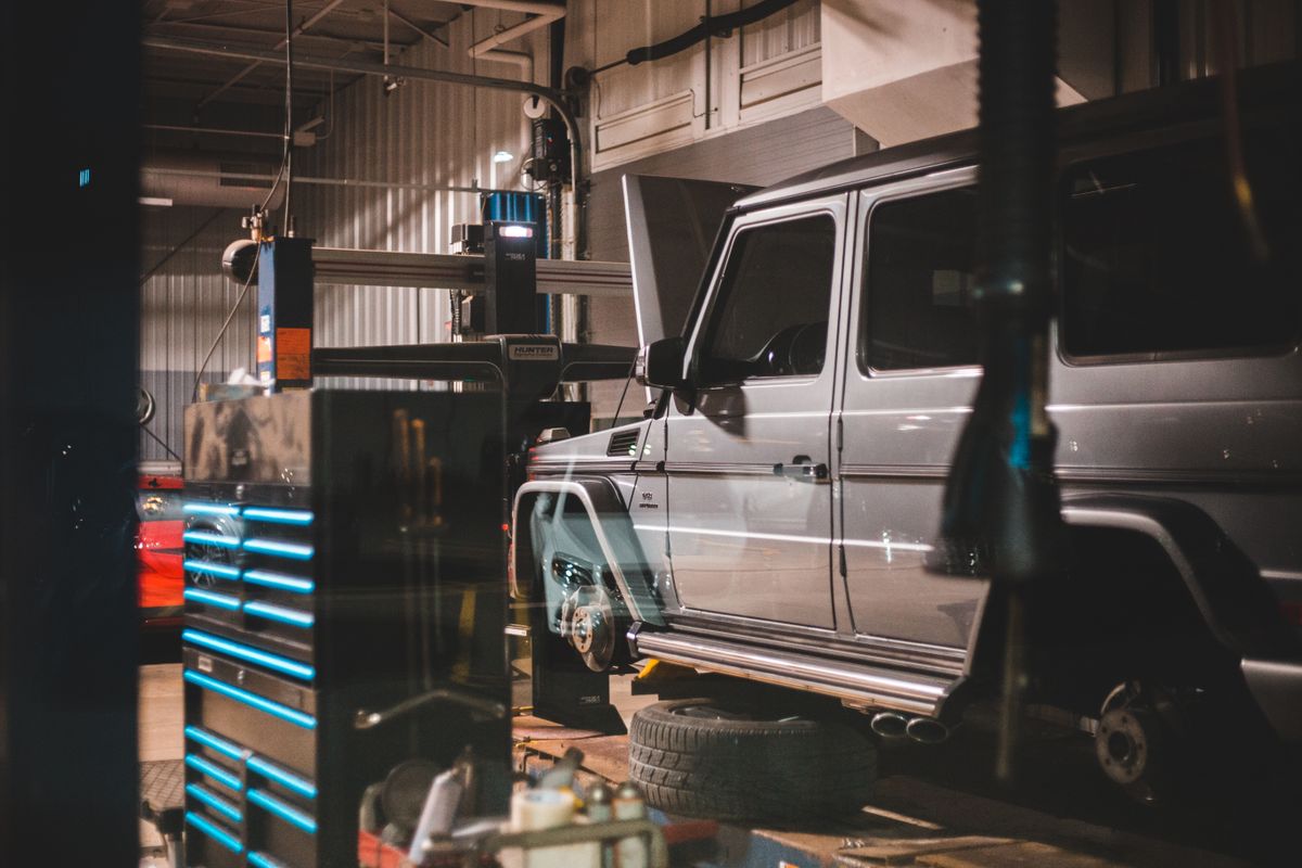 Car raised on a workshop lift surrounded by tyre fitting equipment