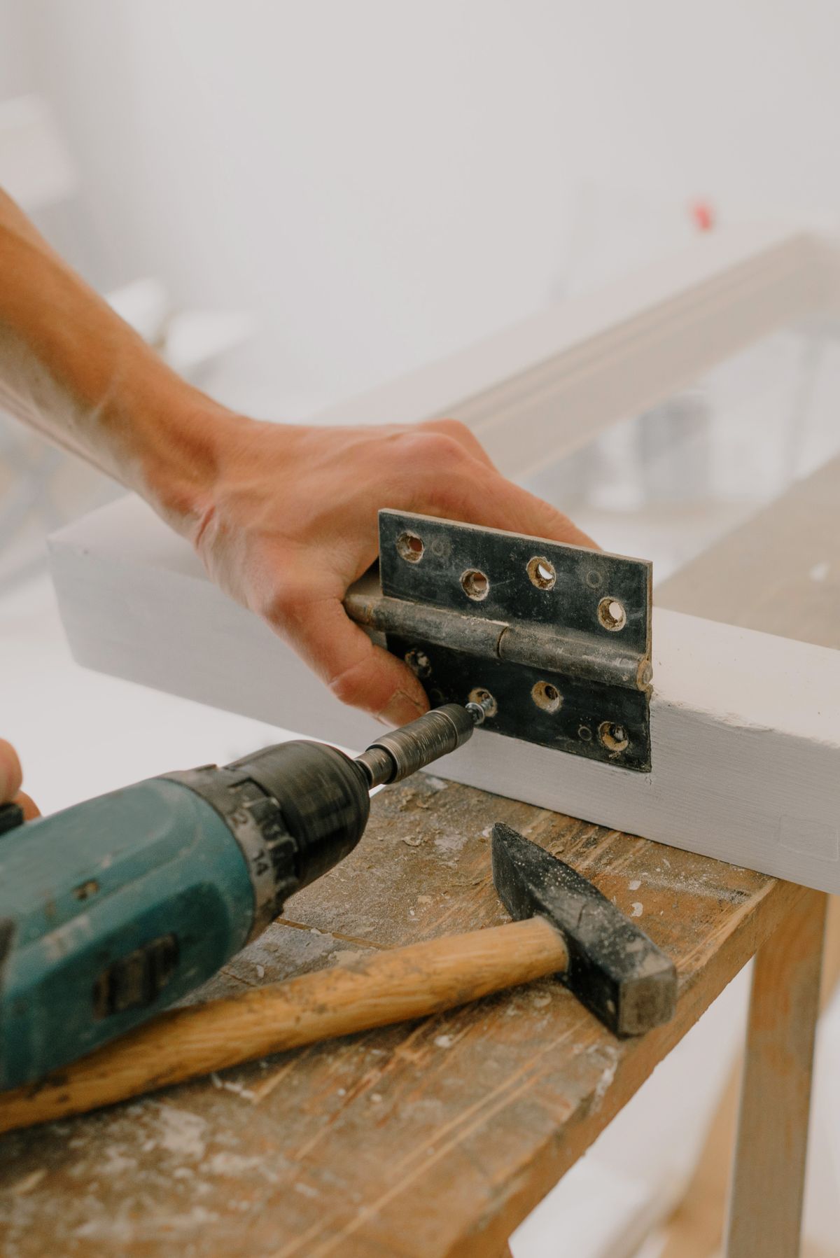 Close-up of a fitter adjusting a hinge on a white uPVC window frame during installation